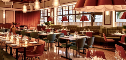 Elegant dining restaurant with warm overhead lights and dark red hues for lamps and seats